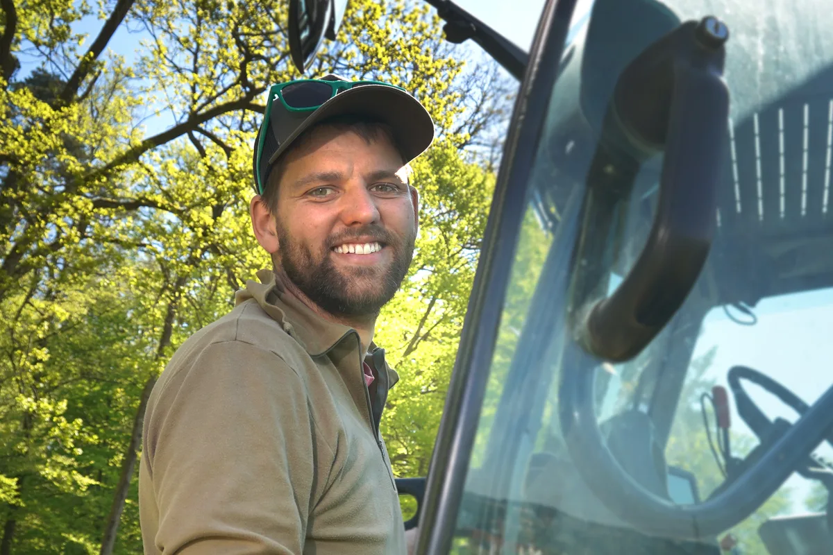 Benjamin Denzler denkt die Landwirtschaft neu, ohne wirklich etwas Neues zu erfinden. Ein Mann mit Mütze und Bart bei seinem Traktor.